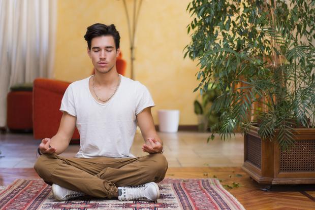 Man in white top, brown pants meditating