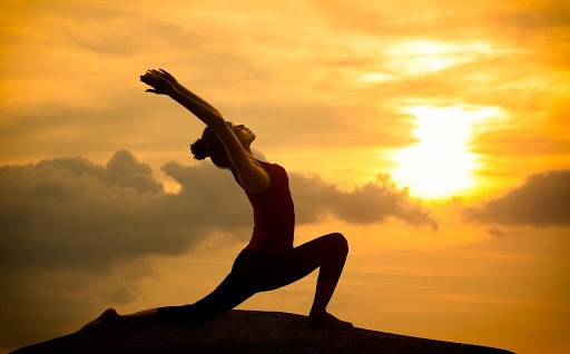 Woamn doing yoga with the sunset in the background